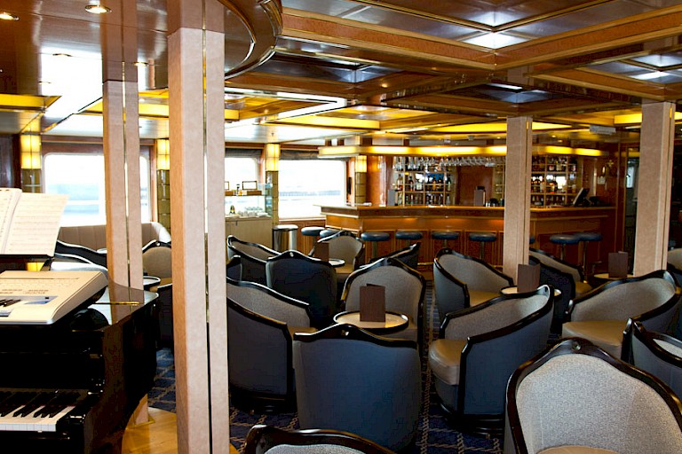 Bar en lounge met panoramaramen en toegang tot buitendekken.